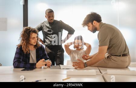 Junge, multiethnische Projekttester fanden gerade einen großen Fehler bei dem Projekt, bevor sie es verkauften Stockfoto