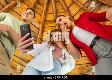 Freundschaft, Freizeit, Sommer, Technologie und Menschen Konzept - Gruppe von lächelnden Freunden machen Selfie mit dem Smartphone im Park Stockfoto