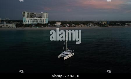 Luftaufnahme eines Segelboots, das vor der Küste vor Anker liegt, während die Sonne über dem ruhigen Meer aufgeht Stockfoto