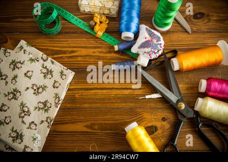 Ein Satz Werkzeuge und Fäden zum Nähen von Kleidung auf Holzhintergrund. Stockfoto