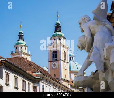 Ljubljana, Slowenien. Türme und Kuppeln der Kathedrale von Ljubljana vom Marktplatz aus zu sehen. Im Vorstehenden werden auch die Figuren auf dem Robba-Brunnen genannt Stockfoto