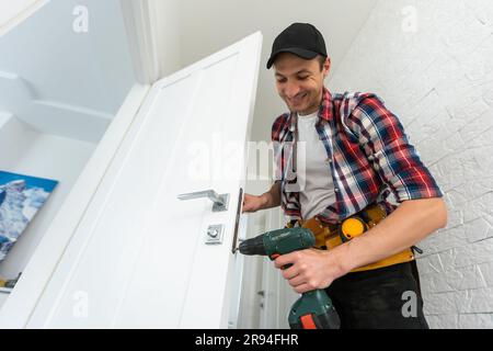 Zimmermann repariert Türschloss. Einbau eines Türgriffs Stockfoto