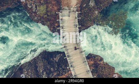 Weißer Hiker aus der Vogelperspektive auf der Holzbrücke über der malerischen Rocky River Gorge im Vestland County, Norwegen. Stockfoto