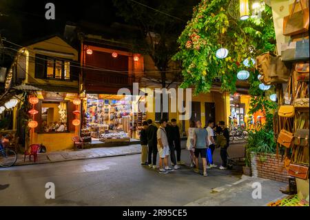 Einheimische und Touristen gehen bei Nacht in die Straßen der Altstadt von Hoi an mit den vielen bunten Lichtern und Papierlaternen. Vietnam. Stockfoto