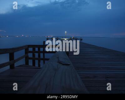 Dunkler Himmel in der Dämmerung entlang einer Barnegat Bay, New Jersey Dock. Fernlichter säumen das Ufergebiet. Stockfoto