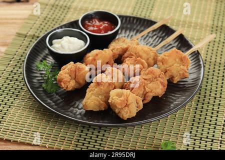 Hausgemachtes gebratenes Hühnchen im japanischen Stil oder Tori Karaage, serviert mit Bambusspieß Stockfoto