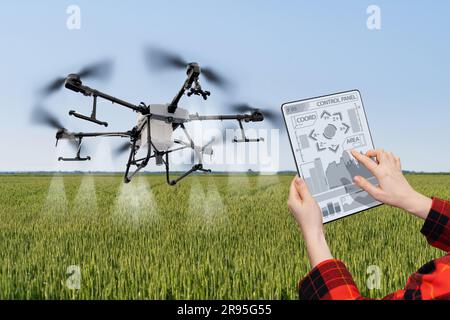 Der Landwirt steuert das Drohnenspray mit einem Tablet. Intelligente Landwirtschaft und Präzisionslandwirtschaft. Stockfoto