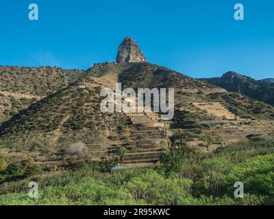 Blick auf den Roque Cano, eine berühmte vulkanische Klippe auf der Nordseite von La Gomera. Ländliche Berglandschaft mit Terrassenfeldern im Tal von Stockfoto