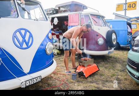 Hannover, Deutschland. 24. Juni 2023. Ein Festivalteilnehmer grillt zwischen Volkswagen Bullis auf dem VW Bus Festival auf dem Messegelände Hannover. Seit Freitag zieht das Festival Tausende Bulli-Fans auf das Messegelände von Hannover. Bis Sonntag werden verschiedene Generationen des Kultfahrzeugs gezeigt. Kredit: Julian Stratenschulte/dpa/Alamy Live News Stockfoto