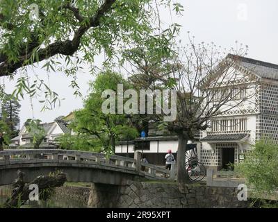 Kurashiki verfügt über eine gut erhaltene Kanalgegend mit den alten Reislagerhäusern, die weiß mit schwarzen Fliesen gestrichen sind, und weinenden Weiden am Ufer. Stockfoto