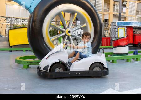 Ein reizendes Kind in einem Kart auf der Kinderbahn Stockfoto