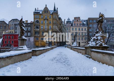 Klodzko, Polen - Januar 2023: Kleine gotische Brücke über den Fluss Mlynowka im Stadtzentrum und im Winter von frischem Schnee bedeckt Stockfoto