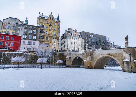 Klodzko, Polen - Januar 2023: Kleine gotische Brücke über den Fluss Mlynowka im Stadtzentrum und im Winter von frischem Schnee bedeckt Stockfoto