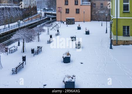 Klodzko, Polen - Januar 2023: Kleiner Entspannungsplatz im Stadtzentrum mit einigen Bänken und Blumen, die im Winter von Schnee bedeckt sind Stockfoto