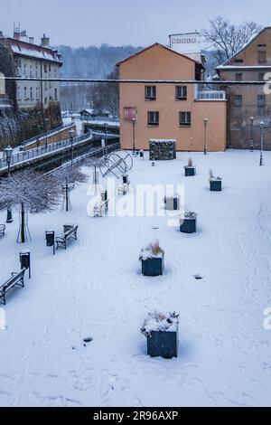 Klodzko, Polen - Januar 2023: Kleiner Entspannungsplatz im Stadtzentrum mit einigen Bänken und Blumen, die im Winter von Schnee bedeckt sind Stockfoto