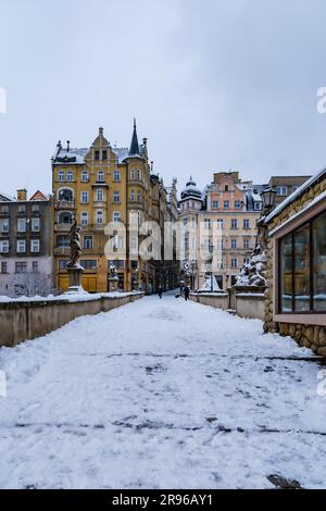 Klodzko, Polen - Januar 2023: Kleine gotische Brücke über den Fluss Mlynowka im Stadtzentrum und im Winter von frischem Schnee bedeckt Stockfoto