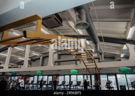 Ein großer Fitnessraum mit einer vielfältigen Gruppe von Personen, die im Hintergrund mit einer Reihe moderner Fitnessgeräte trainieren Stockfoto