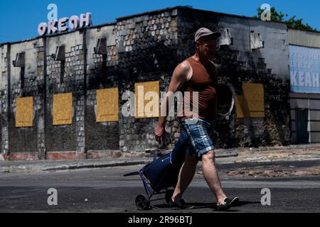 Cherson, Ukraine. 24. Juni 2023. Der Mann läuft an der Straßenfront des zerstörten Gebäudes in Kherson, Ukraine, 24. Juni 2023. Kredit: Ondrej Deml/CTK Photo/Alamy Live News Stockfoto