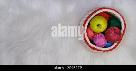 Garne zum Häkeln. Mehrere mehrfarbige Wollfäden im Korb auf weißem, flauschigem Hintergrund. Draufsicht, Webbanner mit Kopierbereich. Co Stockfoto