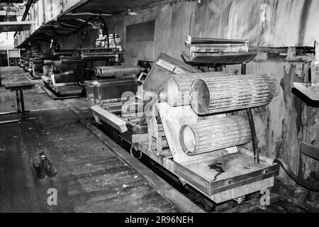 Große Metallrollen mit Zähnen der Zahnräder der Produktionslinie, ein Förderband in der Werkstatt einer petrochemischen Industriemaschine Stockfoto