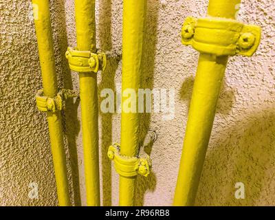 Heizkörper für die Versorgung von Wohnungen mit Heizung. Gelbe Batterierohr für Warmwasserversorgung. Sanitär in einem Wohngebäude. Stockfoto