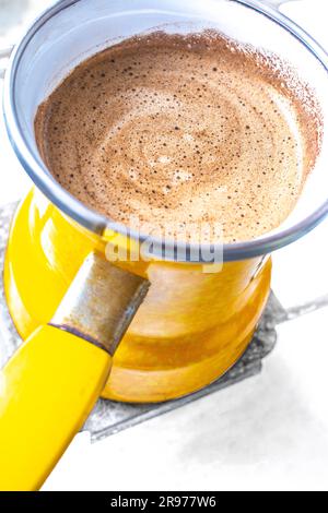 Kücheneinrichtung - Kaffeezubereitung in gelbem truthahn auf Gasherd Kaffee mit Schaum Stockfoto