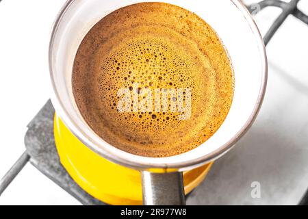 Kücheneinrichtung - Kaffeezubereitung in gelbem truthahn auf Gasherd Kaffee mit Schaum Stockfoto