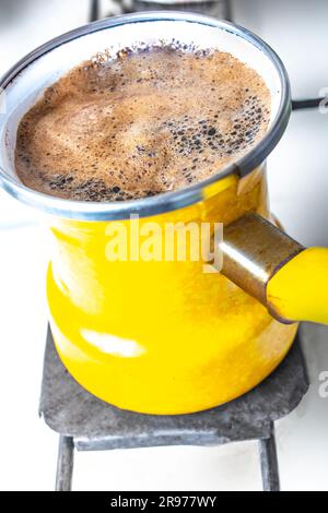 Kücheneinrichtung - Kaffeezubereitung in gelbem truthahn auf Gasherd Kaffee mit Schaum Stockfoto