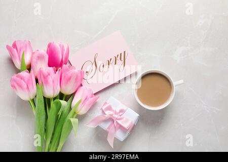 Karte mit Wort „Sorry“, Tasse Kaffee, Geschenkbox und Strauß Tulpen auf hellgrauem Marmortisch, flach liegend Stockfoto