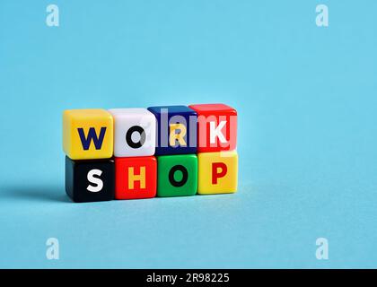 Das Wort Workshop über bunte Würfel auf blauem Hintergrund. Stockfoto