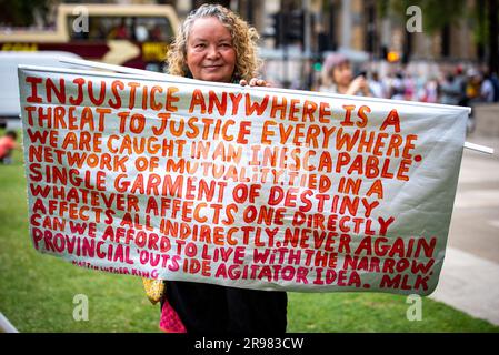 Ein Demonstrant hält ein großes Banner während der "Was zu sagen?" Freier Julian Assange-Protest am Parliament Square in London. „Haben Sie Etwas Zu Sagen?“ Ist eine lebensgroße Bronzeskulptur, in der jeweils drei Figuren dargestellt werden, die auf einem Stuhl des Künstlers Davide Dormino stehen. Der vierte Stuhl ist leer, weil er unser Stuhl ist. Der, auf dem wir uns erheben, um uns auszudrücken oder einfach nur neben Edward Snowden, Julian Assange und Chelsea Manning zu stehen, die den Mut hatten, Nein zu der Einmischung in die globale Überwachung und zu Lügen zu sagen, die zu Krieg führten. Stockfoto