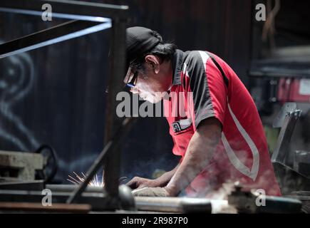 Jakarta, Indonesien - 20. Juni 2023 : Ein Mann in Rot mit schwarzem Hut war Schweißeisen Stockfoto