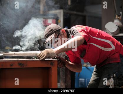 Jakarta, Indonesien - 20. Juni 2023 : Ein Mann in Rot mit schwarzem Hut war Schweißeisen Stockfoto