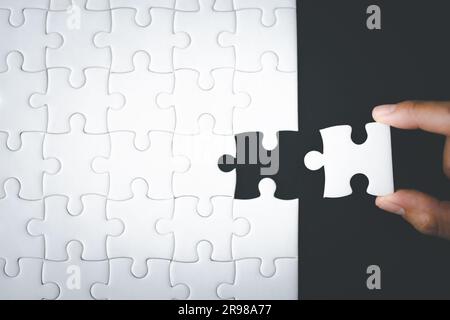 Das Konzept des Geschäfts, das letzte Puzzleteil von Hand zu platzieren, um die Mission abzuschließen. Stockfoto