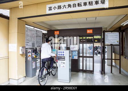 Kyoto Japan, männlicher Radfahrer auf dem Fahrrad betritt einen sicheren Parkplatz für Fahrräder und Motorroller Motorräder in der Innenstadt von Kyoto, Japan, Asien 2023 Stockfoto