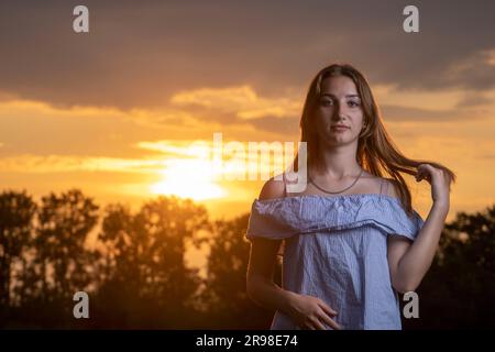 Ein junges Mädchen im Hintergrund des Sonnenuntergangs. Stockfoto