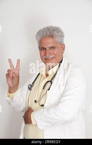 Leitende Ärztin im Laborkittel mit überkreuzten Armen vor weißem Hintergrund. Glücklicher indischer Arzt im weißen Mantel. Selbstbewusst. Stockfoto