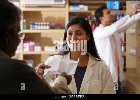 Chemiker Mann in der Apotheke - Drogeriemarkt. Nahaufnahme des Apothekers in der Krankenhausapotheke. Unterstützung für Kunden, Senior Old man Kunde am Schalter. Stockfoto