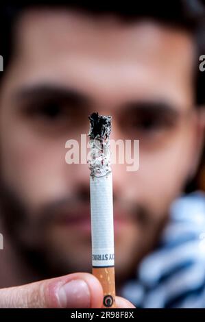 Istanbul, Türkei - 11. Juni 2021: Junger Mann mit einer Lucky Strike Zigarette gegen sein Gesicht. Stockfoto