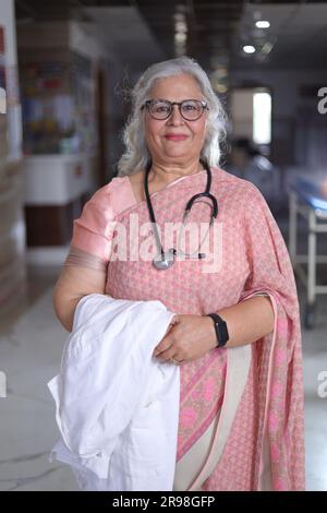 Porträt einer Oberärztin mit überkreuzten Armen im Krankenhauskorridor. Happy Indian Doctor White Laborkittel Stockfoto