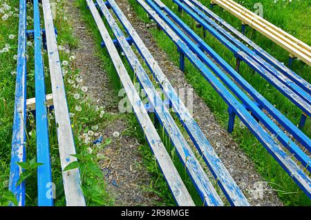 Vier Holzbänke sind blau lackiert, eine ist lackfrei Stockfoto