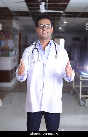 Glücklicher indischer Senior Medical professionell Standbild im Flur des Krankenhauses gekleidet in Peelings und Labormänteln, mit Stethoskopen. Stockfoto