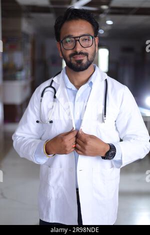 Glücklicher indischer Senior Medical professionell Standbild im Flur des Krankenhauses gekleidet in Peelings und Labormänteln, mit Stethoskopen. Stockfoto