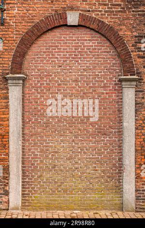 Roter Backsteinwandfragment mit Bogenform, architektonische Details Stockfoto