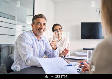 Lächelnde lateinische Führungskraft, die bei einem Teammeeting mit verschiedenen Kollegen zusammenarbeitet Stockfoto