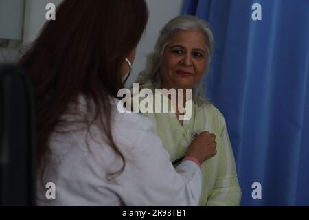 Junger Arzt, der mit Seniorpatienten in der Arztpraxis sitzt. Ältere Patientin im ausführlichen Gespräch mit Ärztin, Herzfrequenzkontrolle. Stockfoto