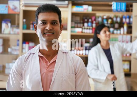 Apotheker Chemiker Indianer steht in Apotheke - Drogerie. Nahaufnahme des Apothekers in der Krankenhausapotheke. Apotheker, der Kunden hilft Stockfoto