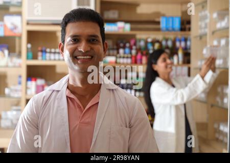 Apotheker Chemiker Indianer steht in Apotheke - Drogerie. Nahaufnahme des Apothekers in der Krankenhausapotheke. Apotheker, der Kunden hilft Stockfoto