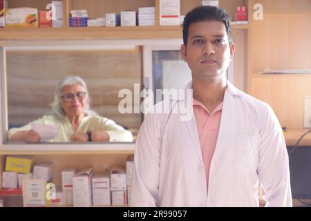 Apotheker Chemiker Indianer steht in Apotheke - Drogerie. Nahaufnahme des Apothekers in der Krankenhausapotheke. Apotheker, der Kunden hilft Stockfoto