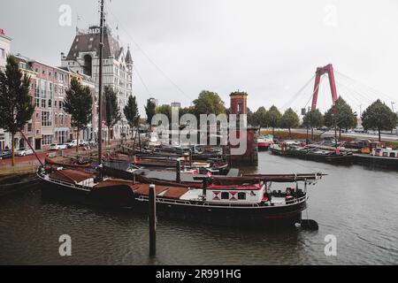 Rotterdam, NL - 6. Oktober 2021: Boote im alten Hafen von Rotterdam, Oude Haven, und das Weiße Haus, Witte Huis Gebäude im Hintergrund bei Regen Stockfoto